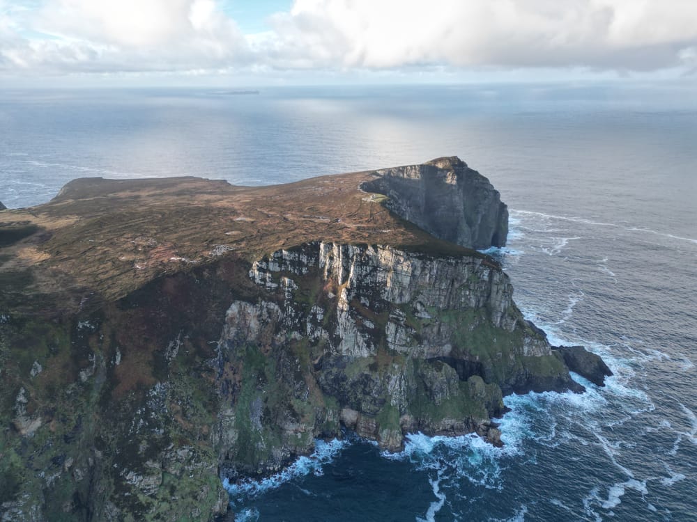 a rocky cliff with a body of water below