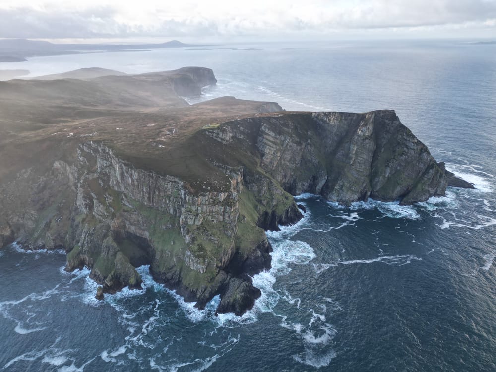 a rocky cliff with waves crashing against it