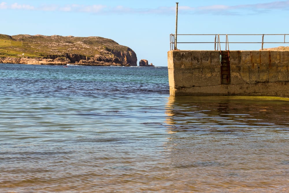 a body of water with a concrete wall and a bridge in the background
