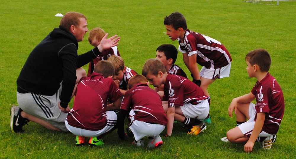 a group of boys in uniform kneeling on grass
